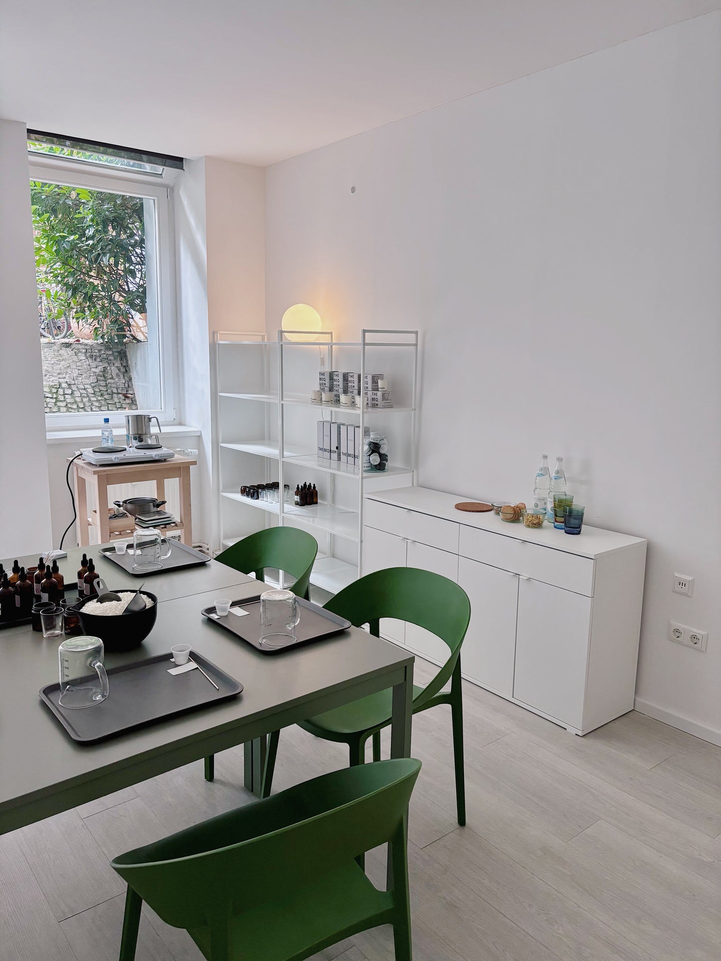 Modern kitchen with white cabinets, green chairs, and a window view. Candle Making Workshop "Make Two Perfumed Candles" with Anastasia in Berlin, Germany, by subcultours