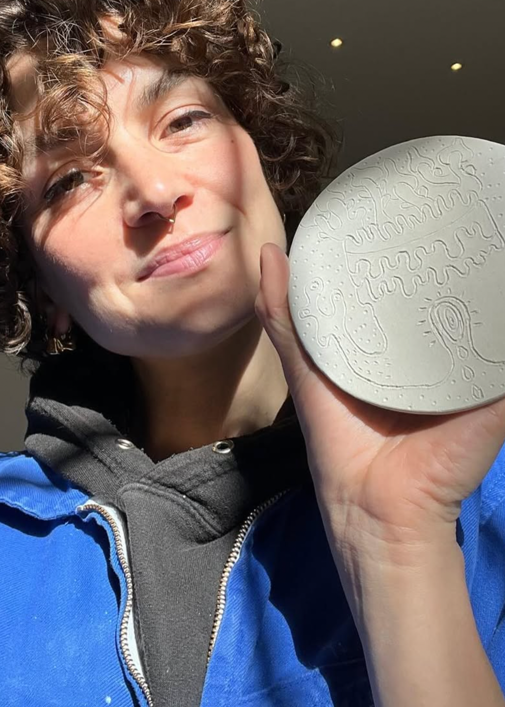 Person holding a round, textured object with intricate designs