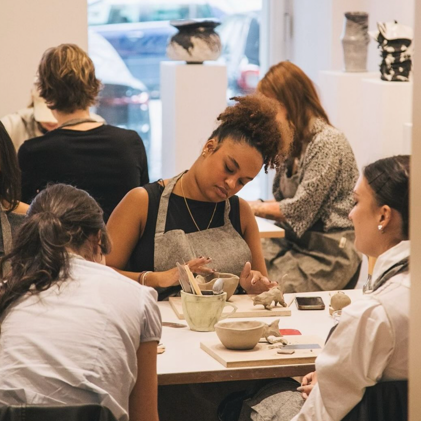 Group of people working on pottery in a studio setting