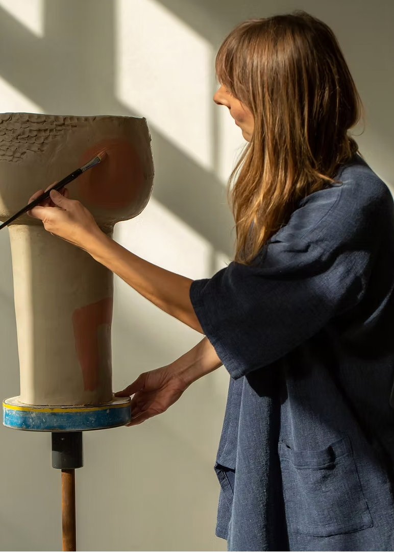 Person interacting with a large cylindrical object against a plain wall