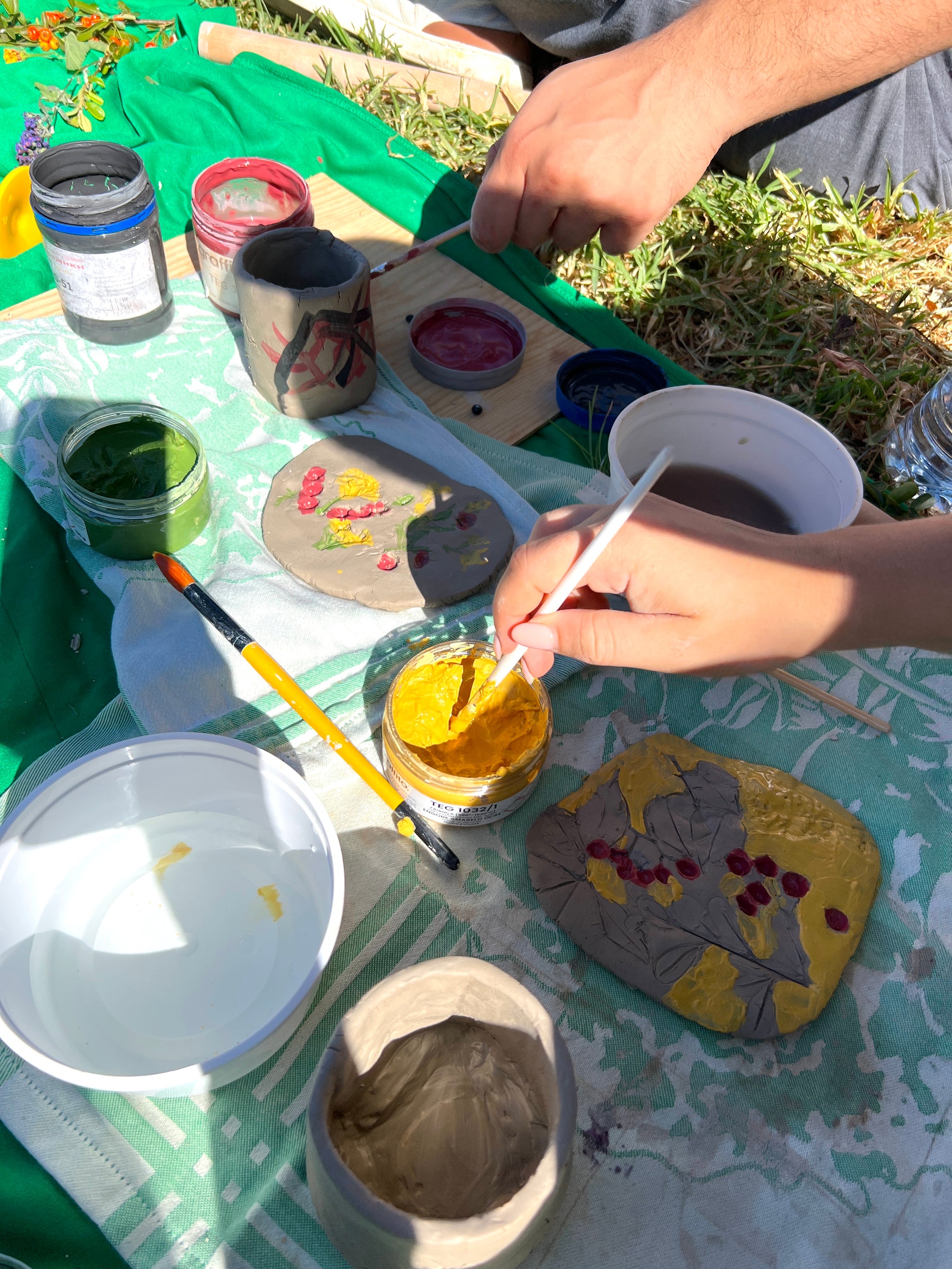 Person painting rocks with various colors on a table outdoors