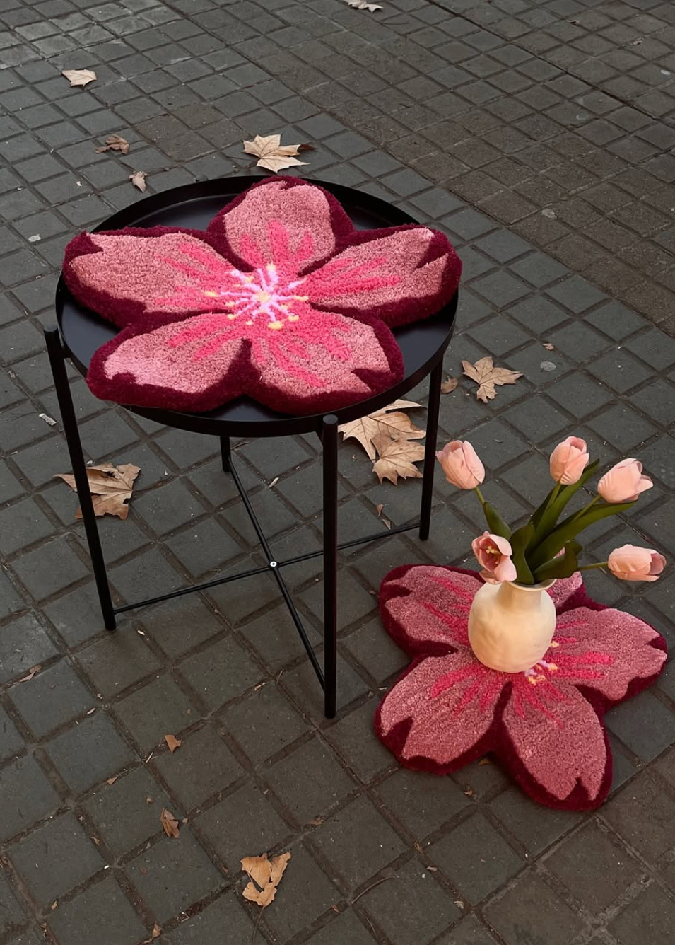 Decorative pink flower-shaped mats on a black metal stool outdoors.