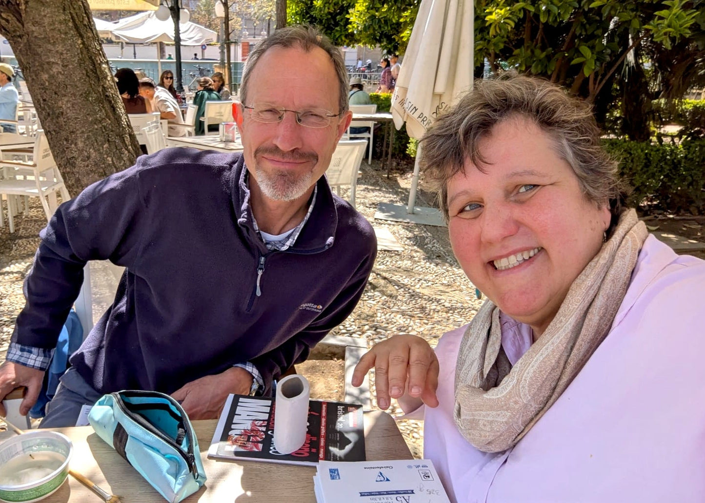 Two people sitting at an outdoor table with a scenic background