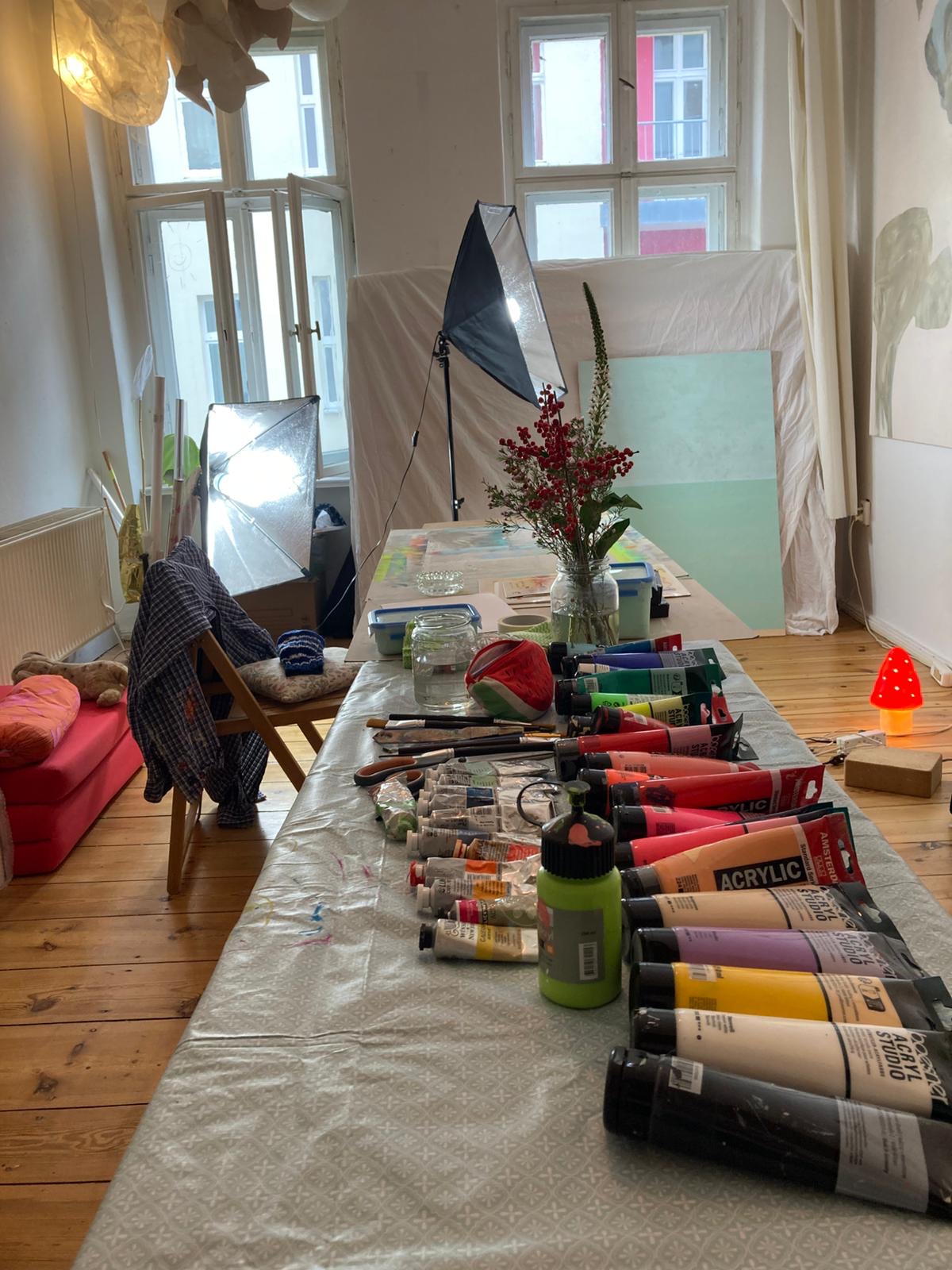 Art supplies on a table with a window and studio lights in the background