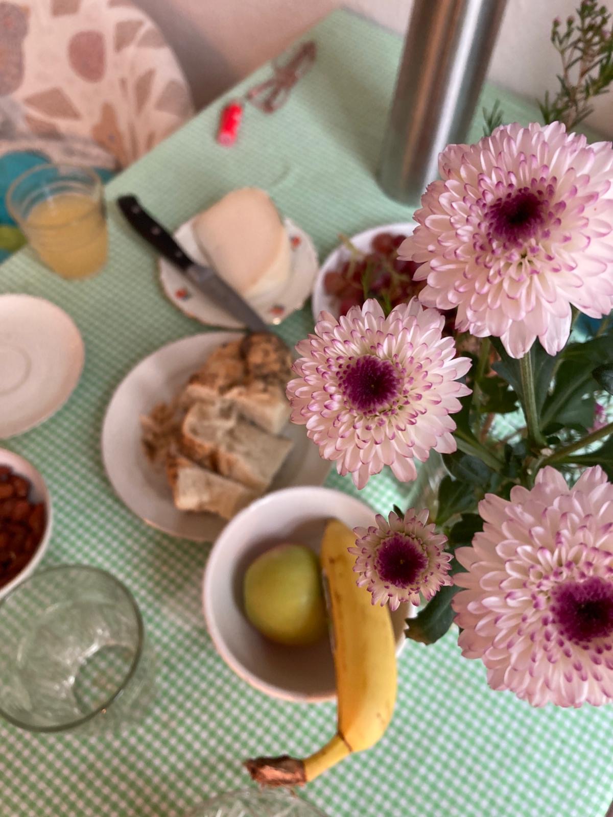 Table with breakfast items and pink flowers on a green tablecloth