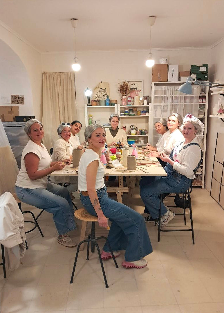 Group of women sitting around a table in a room with shelves and decor.