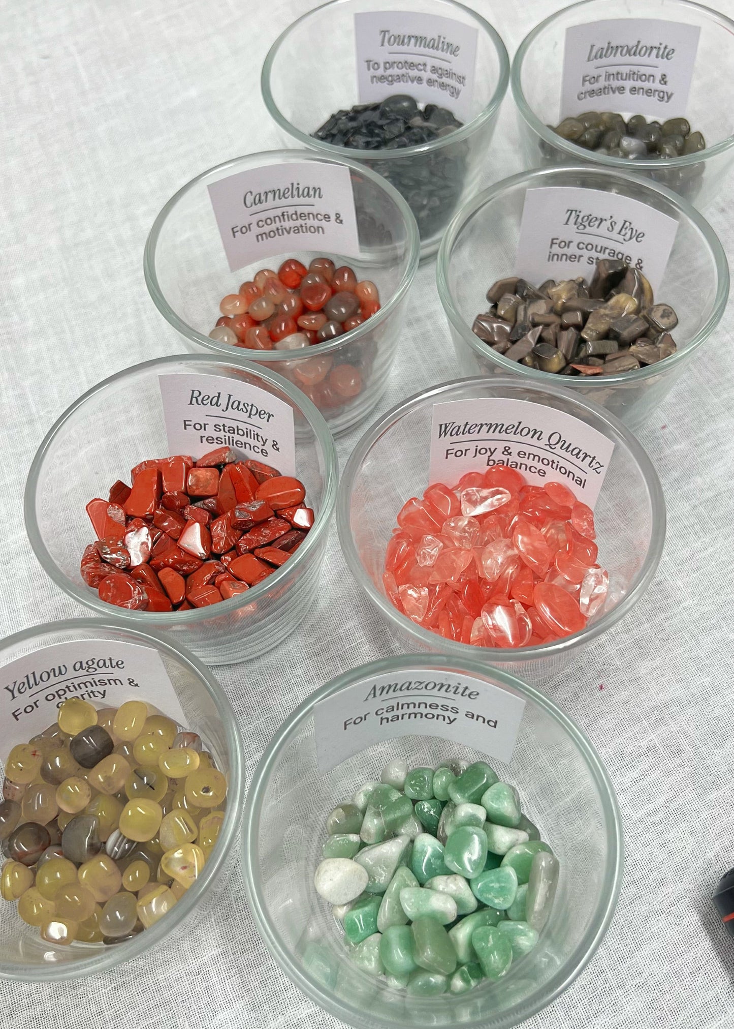 Glass bowls with various types of stones and crystals on a textured surface
