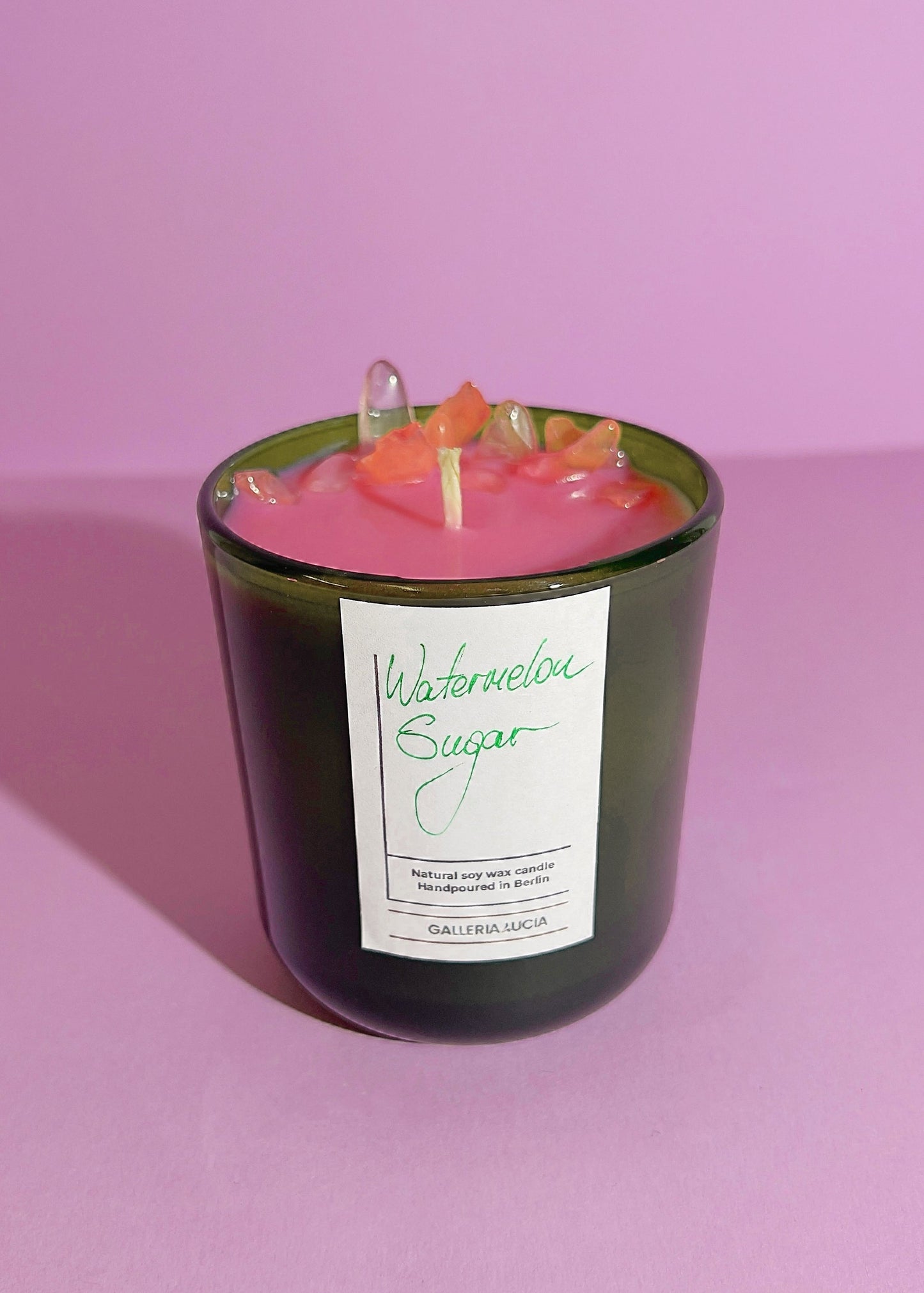 Candle with watermelon flavor in a green glass jar on a pink background