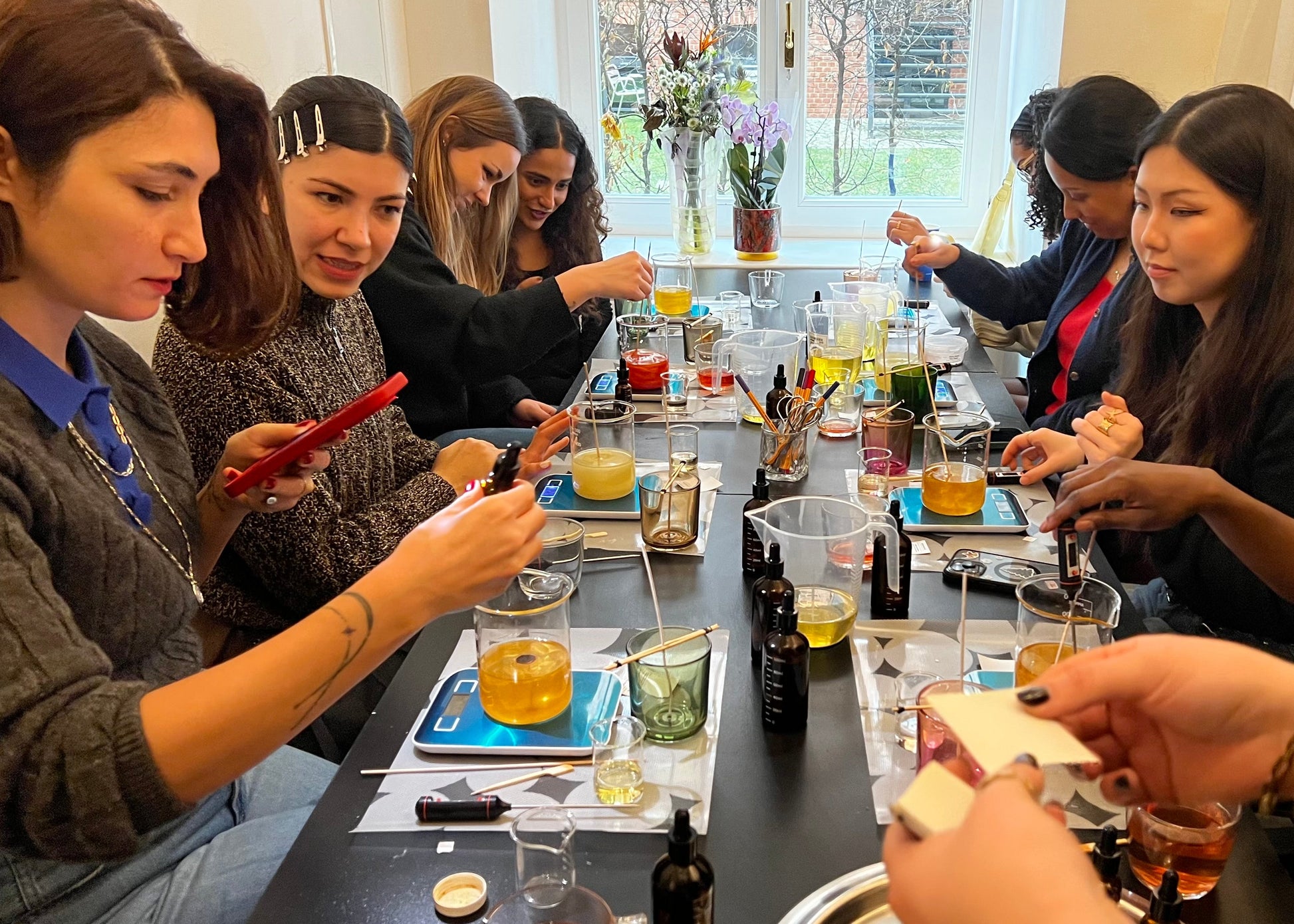 Group of people gathered around a table for a tasting event, with drinks and snacks.