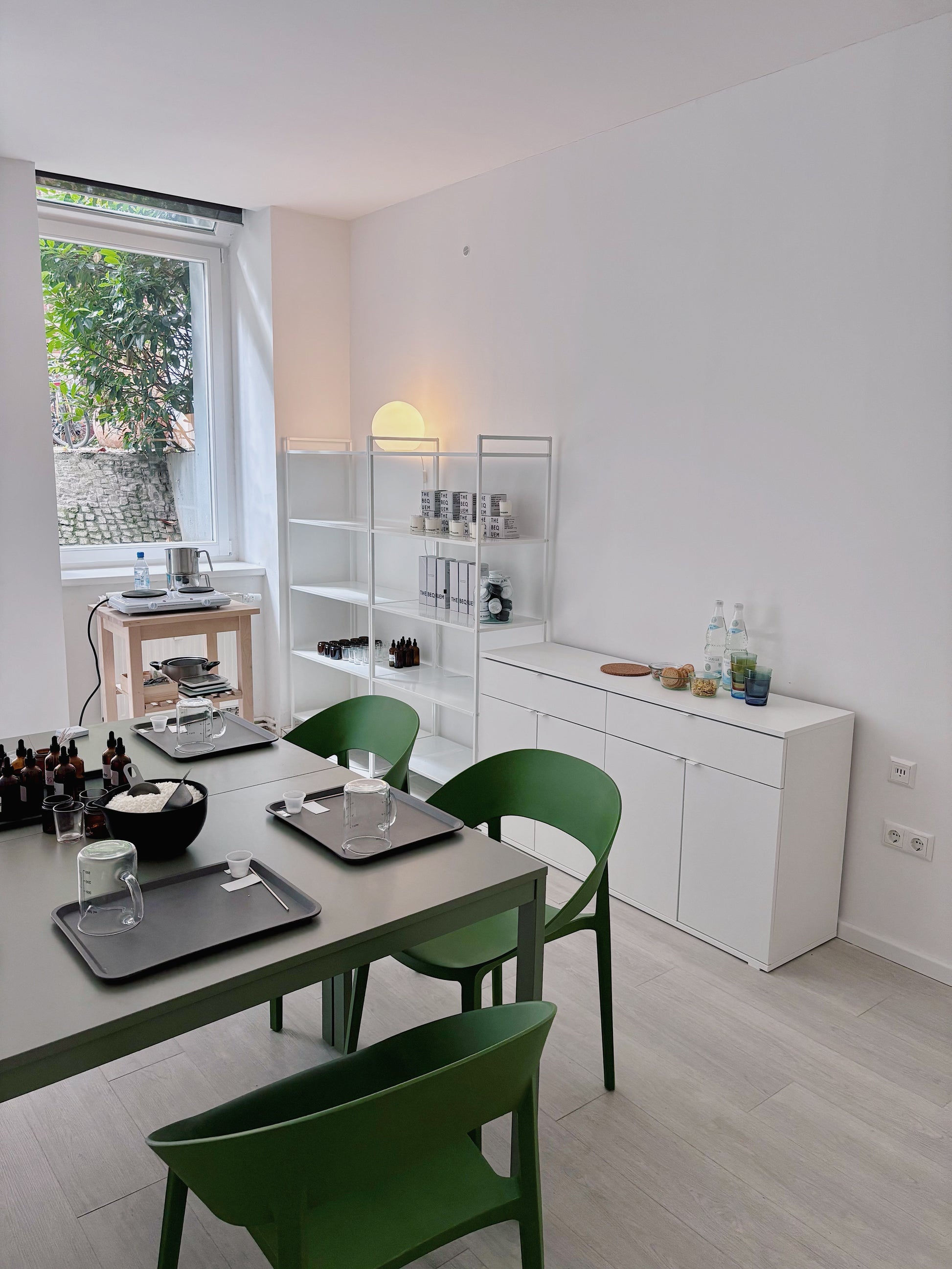 Modern kitchen with white cabinets, green chairs, and a window view. Candle Making Workshop "Make Two Perfumed Candles" with Anastasia in Berlin, Germany, by subcultours