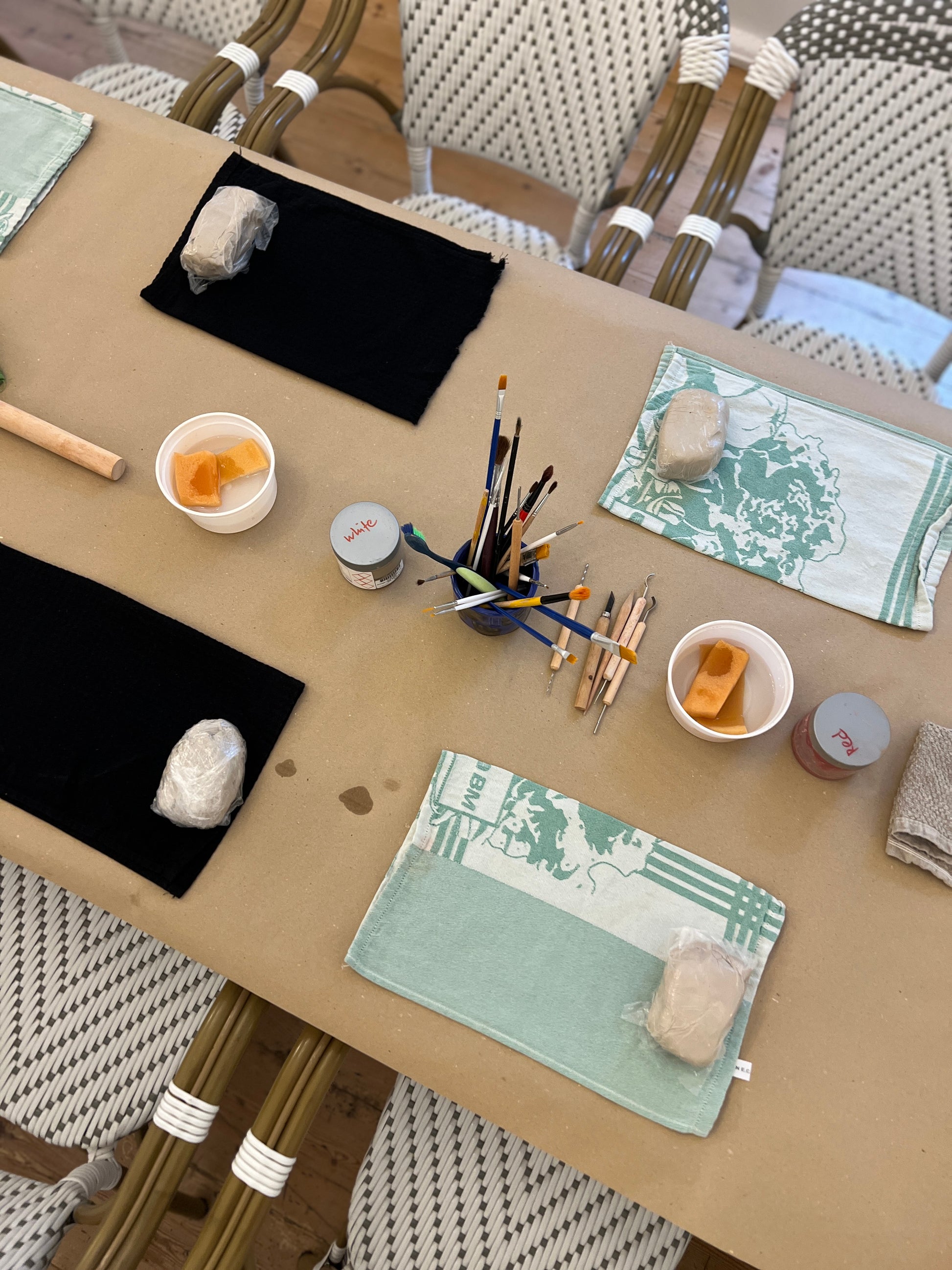 Table with art supplies including paintbrushes, canvases, and paint on a wooden table.