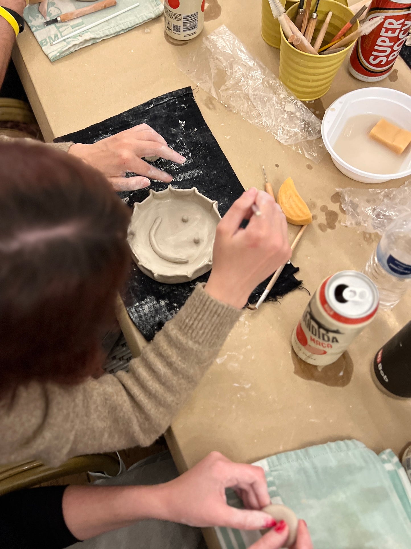 Person working with clay on a pottery wheel in a workshop setting.