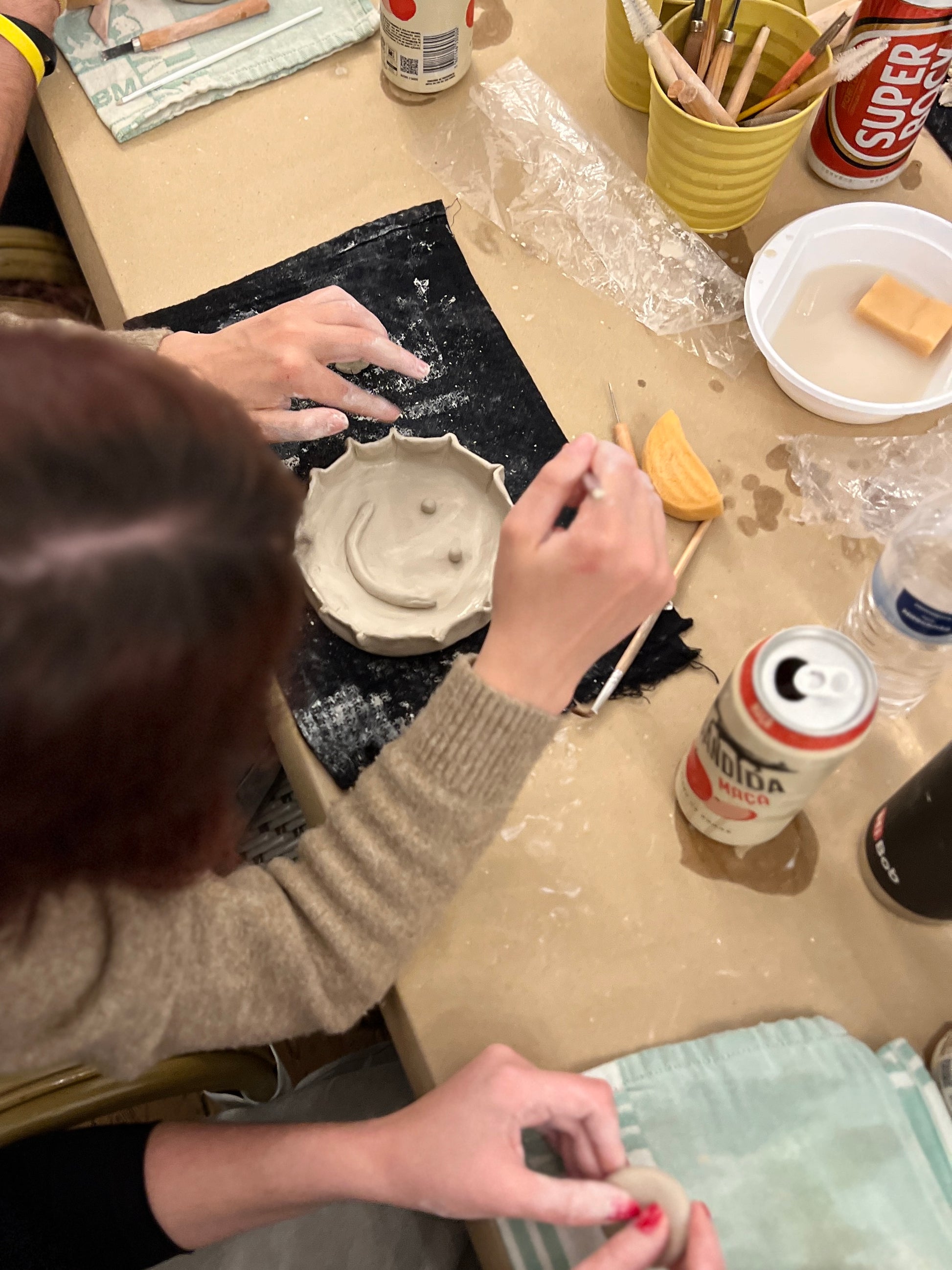 Person working with clay on a pottery wheel in a workshop setting.