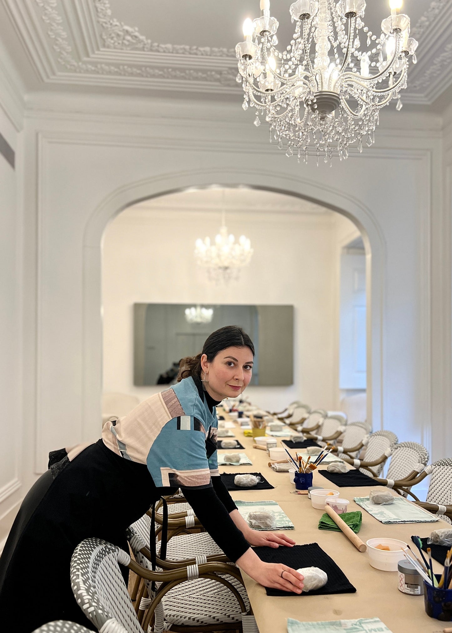 Woman in a stylish room with a chandelier and dining table.