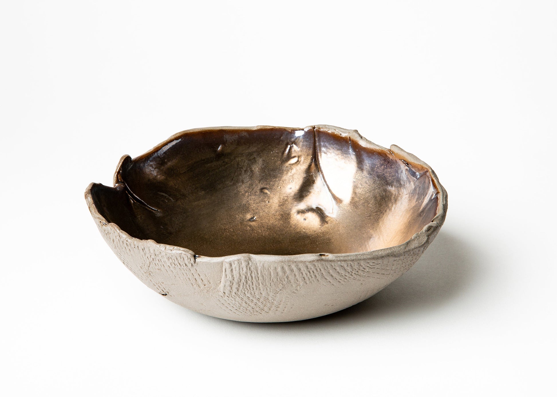 A handmade ceramic bowl with a textured, organic cracked exterior and a metallic bronze interior, shown on a clean white background.