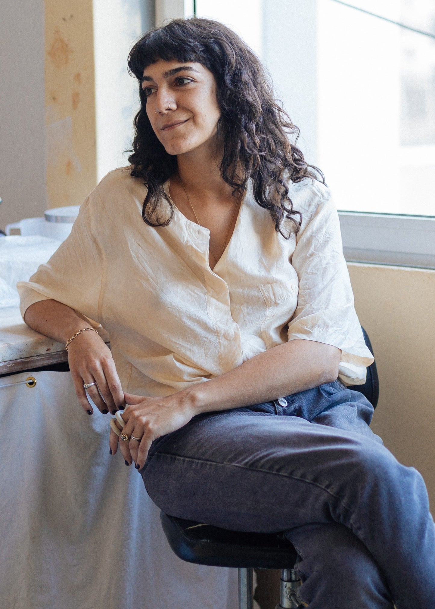 Woman sitting on a stool in a room with a window and medical equipment.