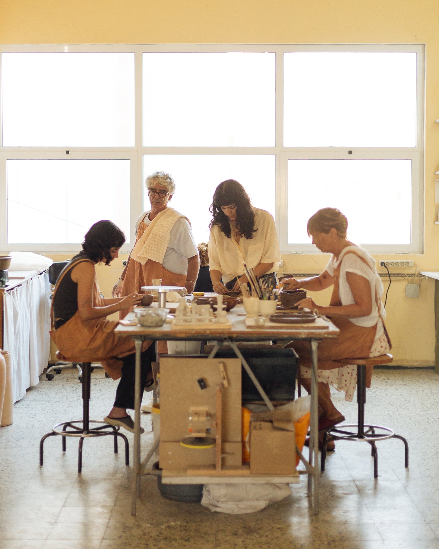 Four women sitting around a table in a room with large windows.