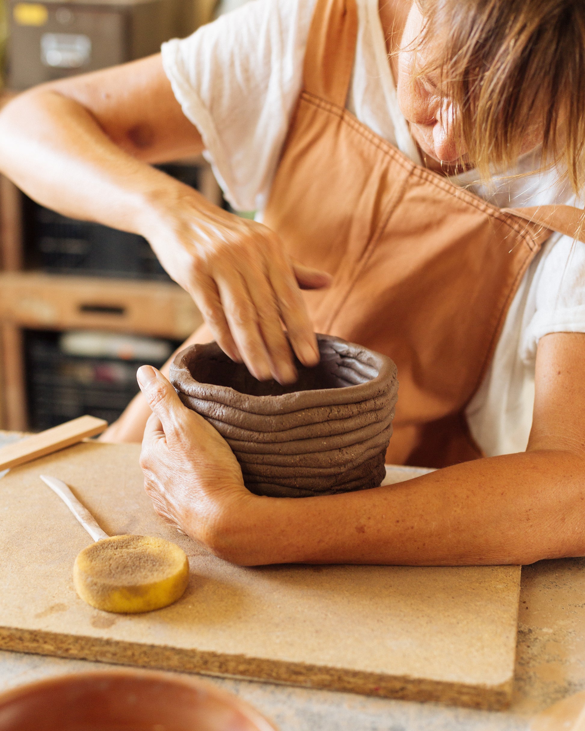 Person working with clay on a pottery wheel in a workshop setting