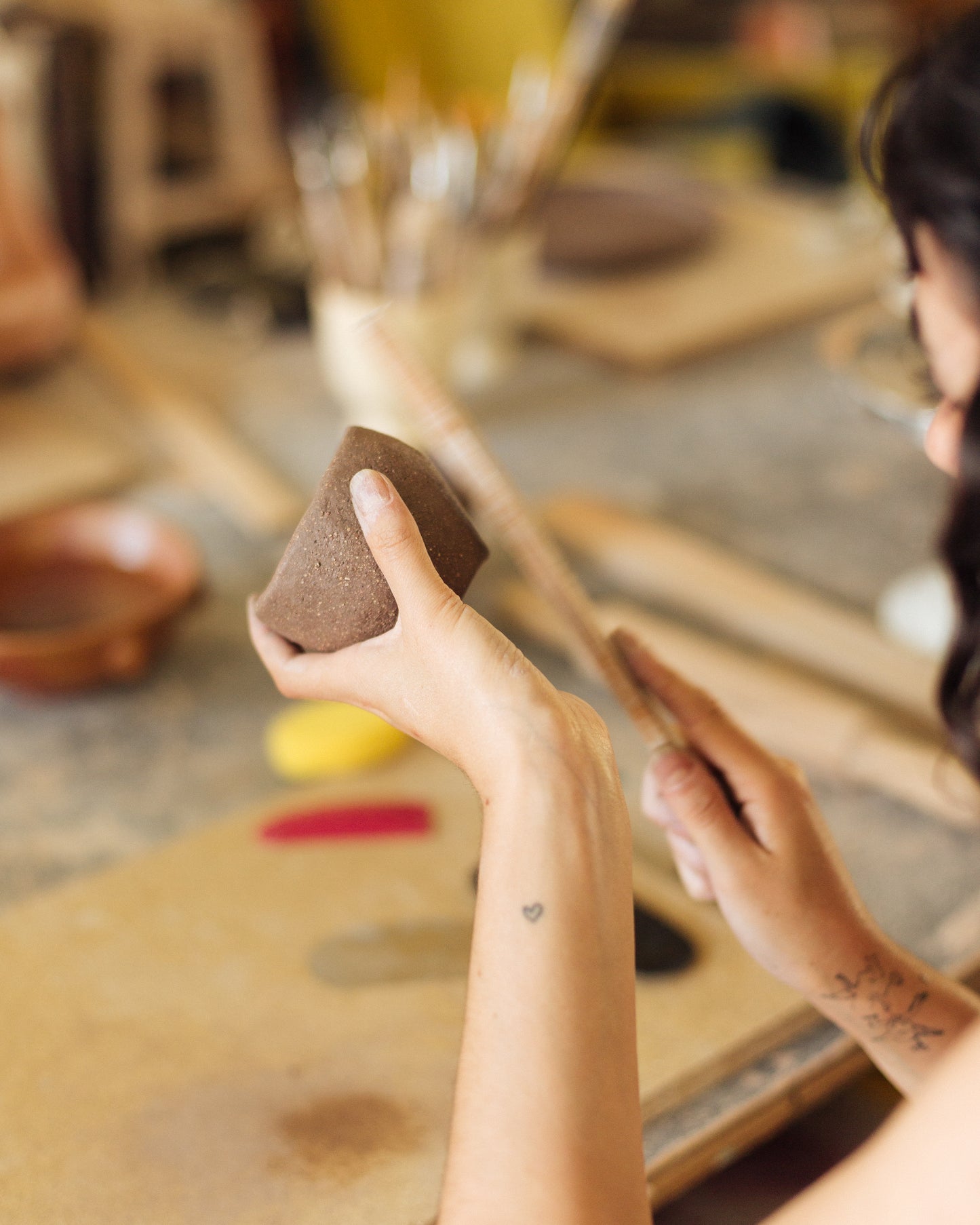 Person holding a brown sponge in a pottery studio