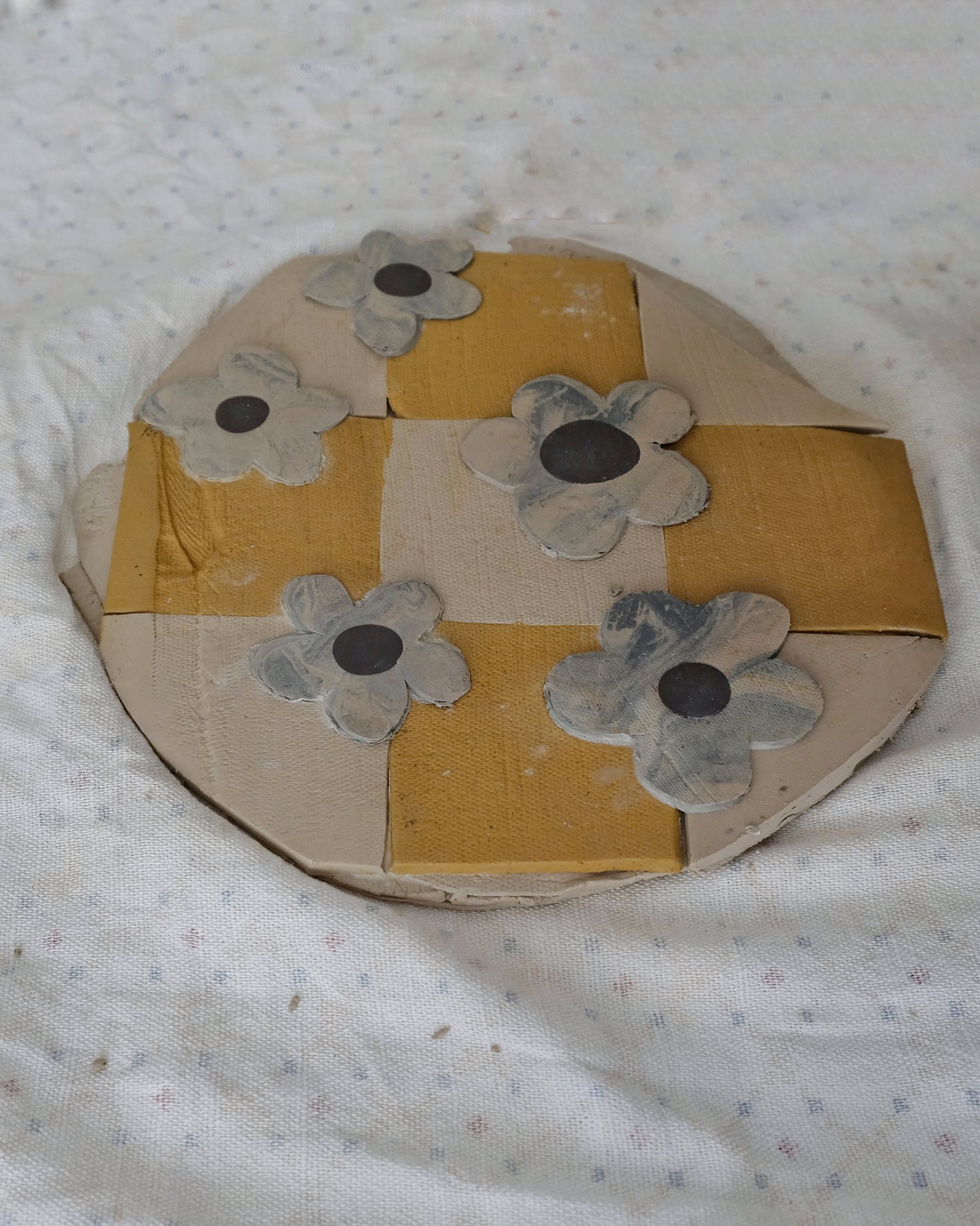 Round cardboard object with floral patterns on a textured white background