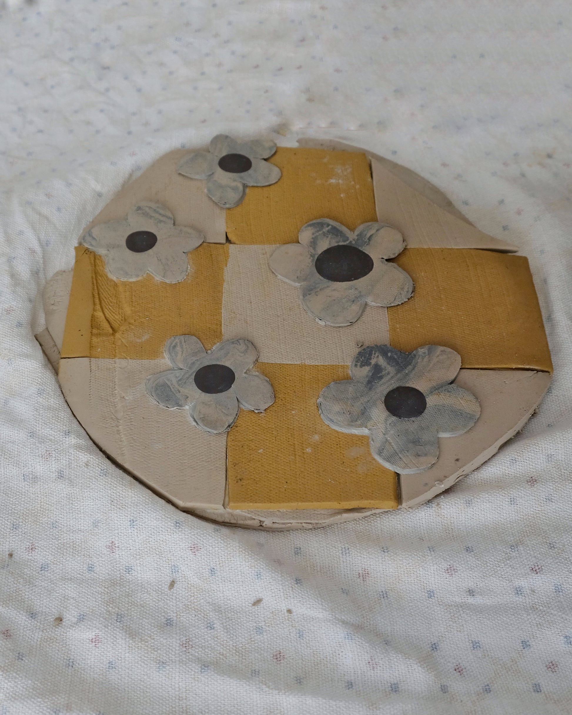 Round cardboard object with floral patterns on a textured white background