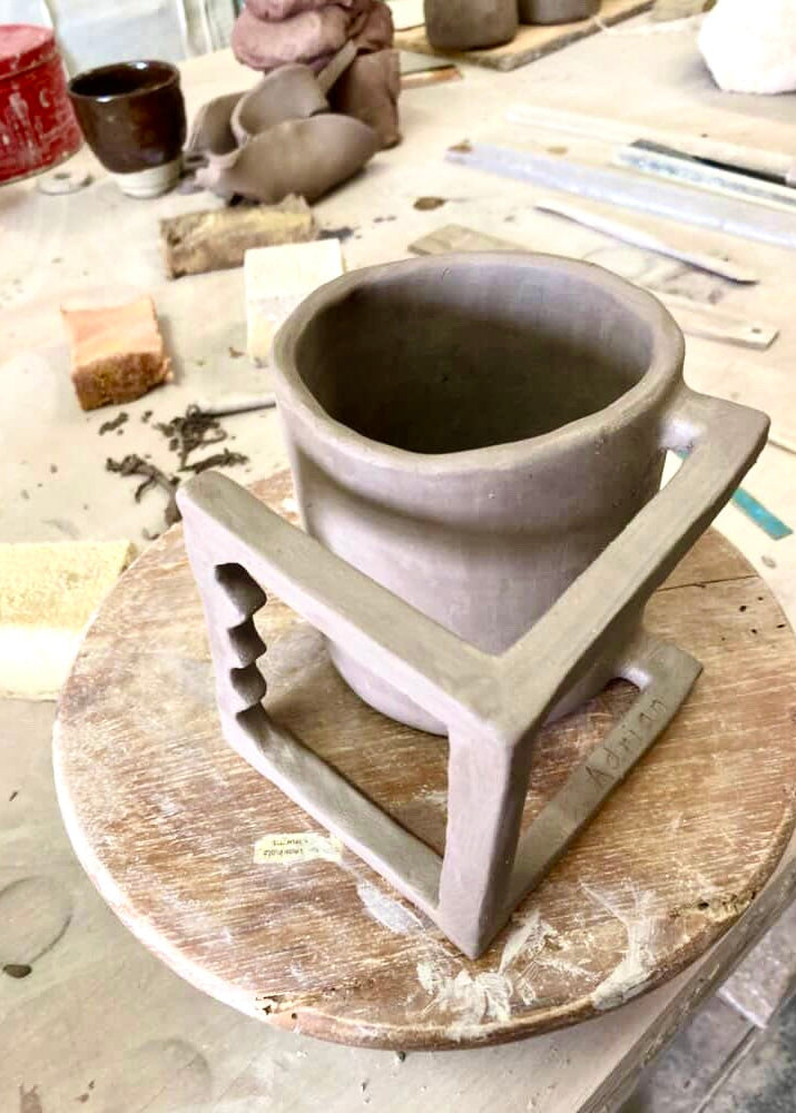 Clay pot on a pottery wheel with tools and materials in the background