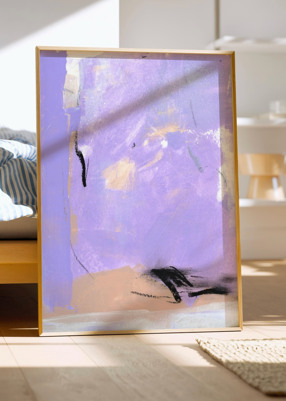 A framed abstract art print featuring a lavender purple background with black and beige brushstrokes, leaning against a wooden bed frame in a sunlit bedroom.