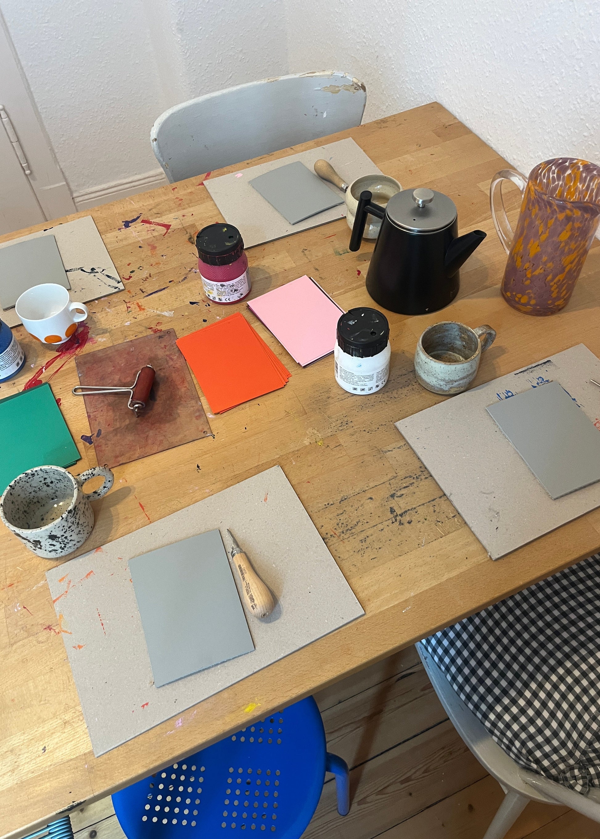 Top-down view of a wooden table with various items including a coffee maker, mugs, and stationery.