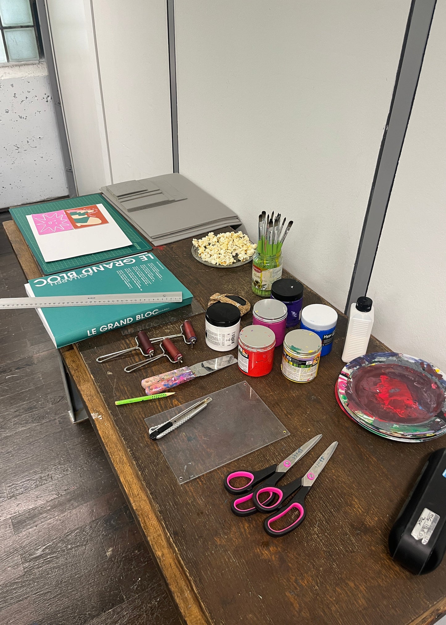 Desk with art supplies including paint jars, brushes, and scissors.
