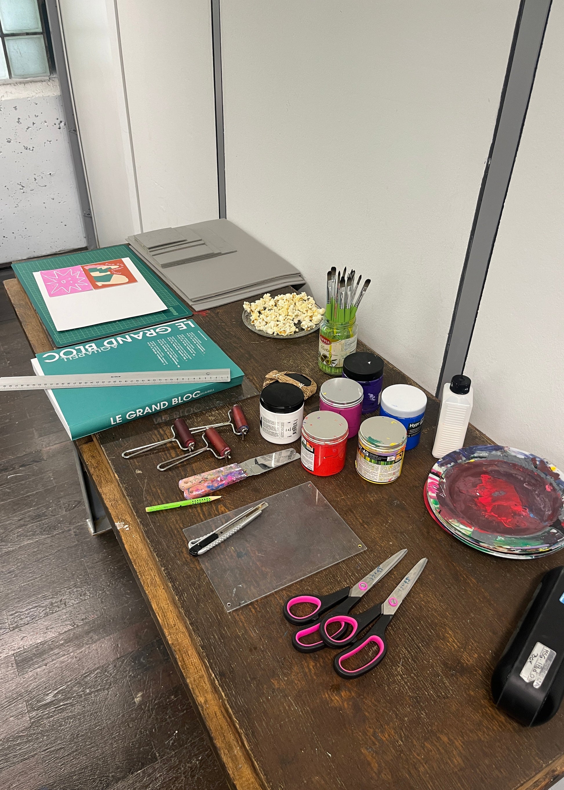 Desk with art supplies including paint jars, brushes, and scissors.