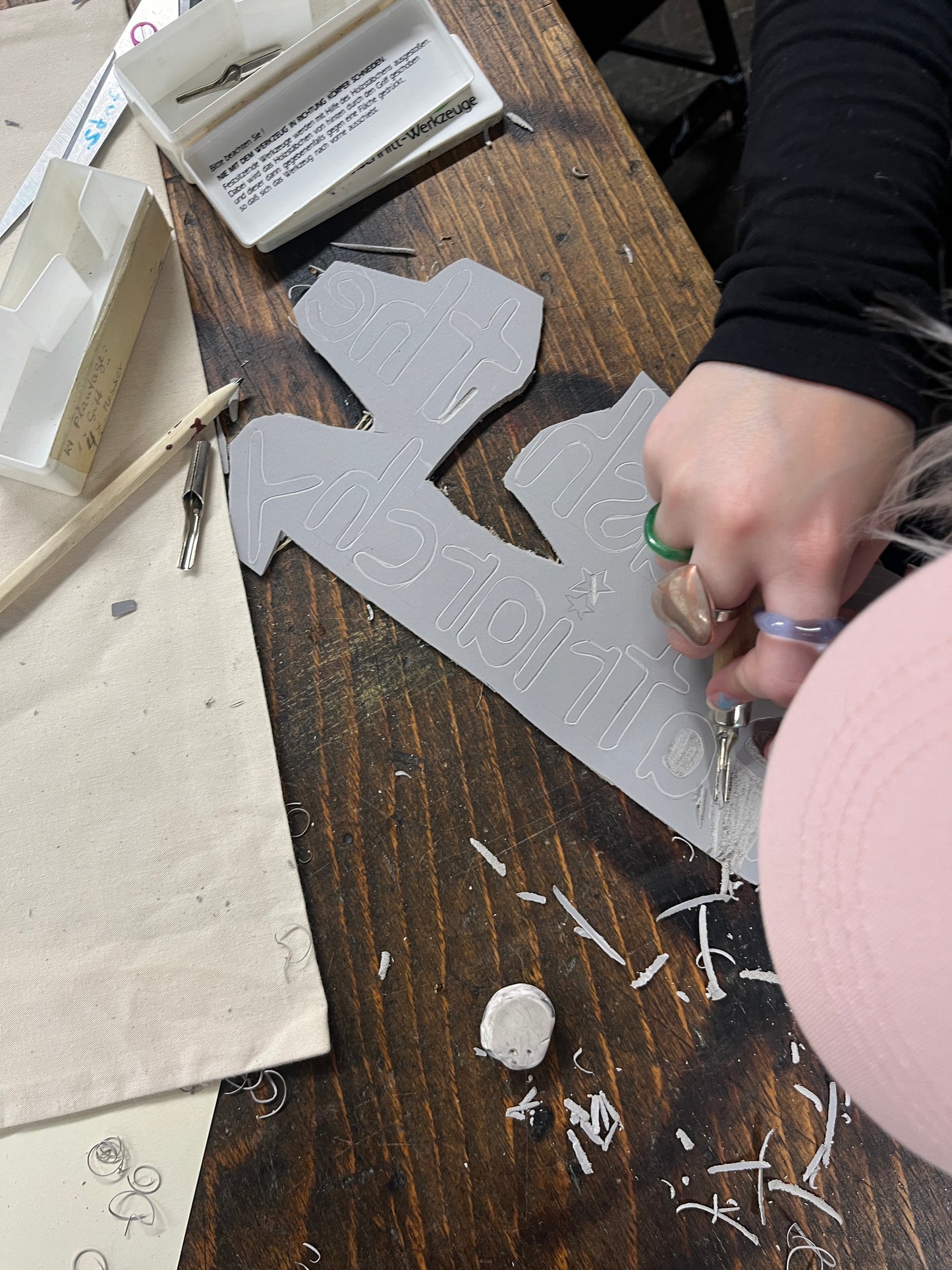 Person cutting out shapes from paper with scissors on a wooden table.