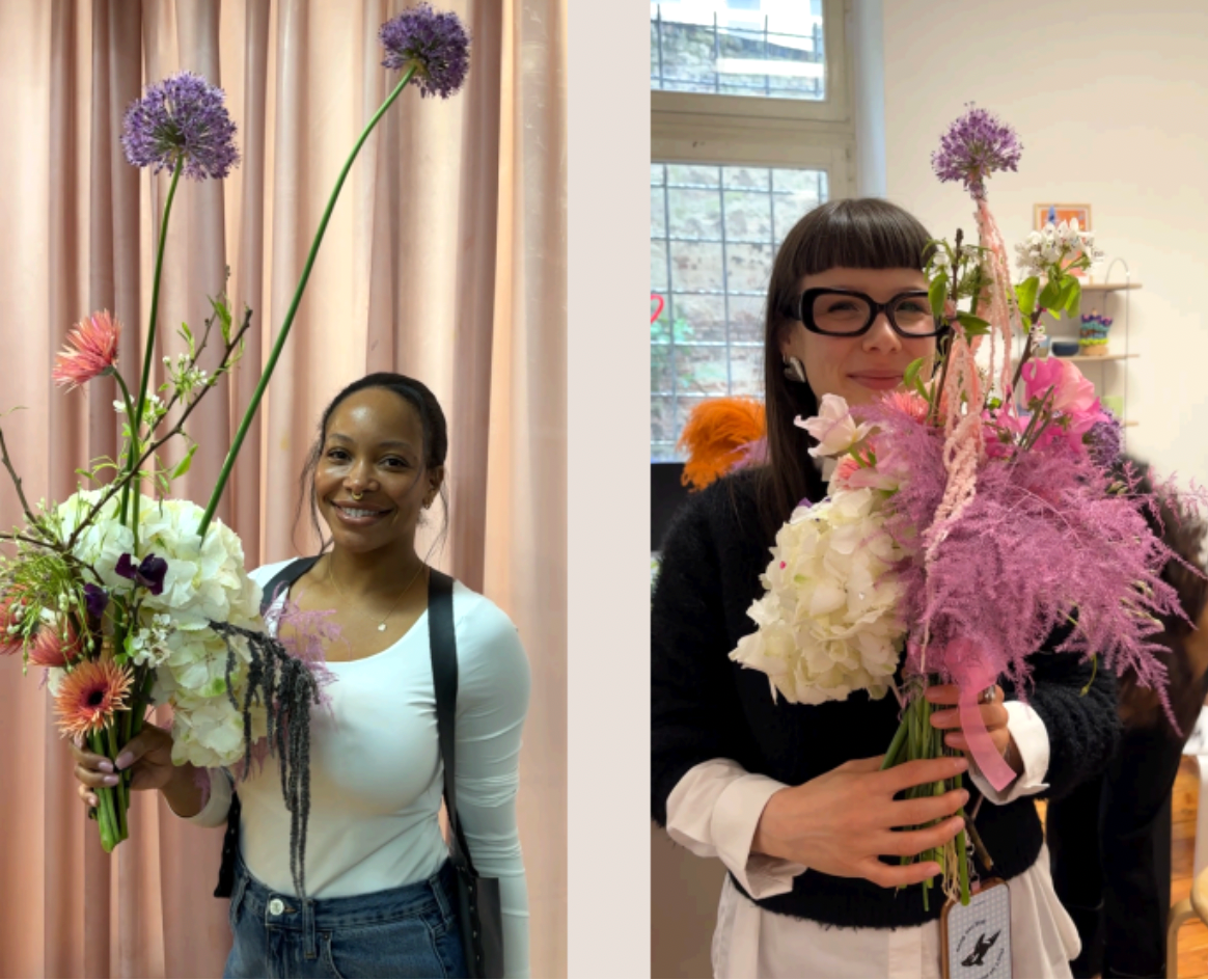 Two people holding flower bouquets indoors with a neutral background
