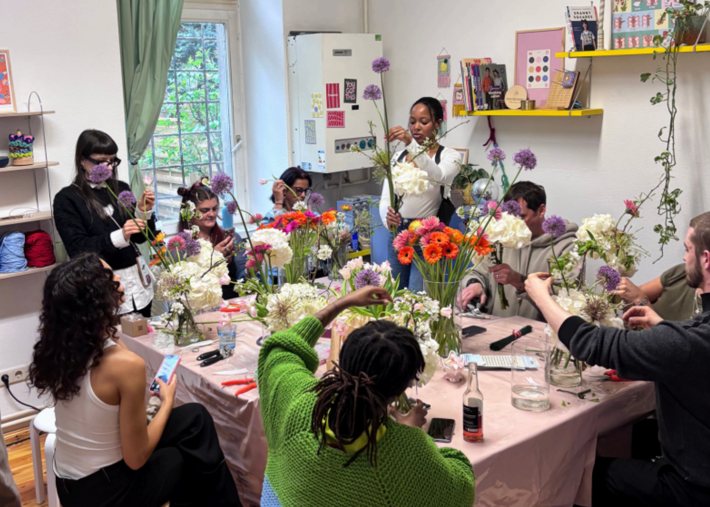 Group of people participating in a floral arrangement workshop in a bright room.