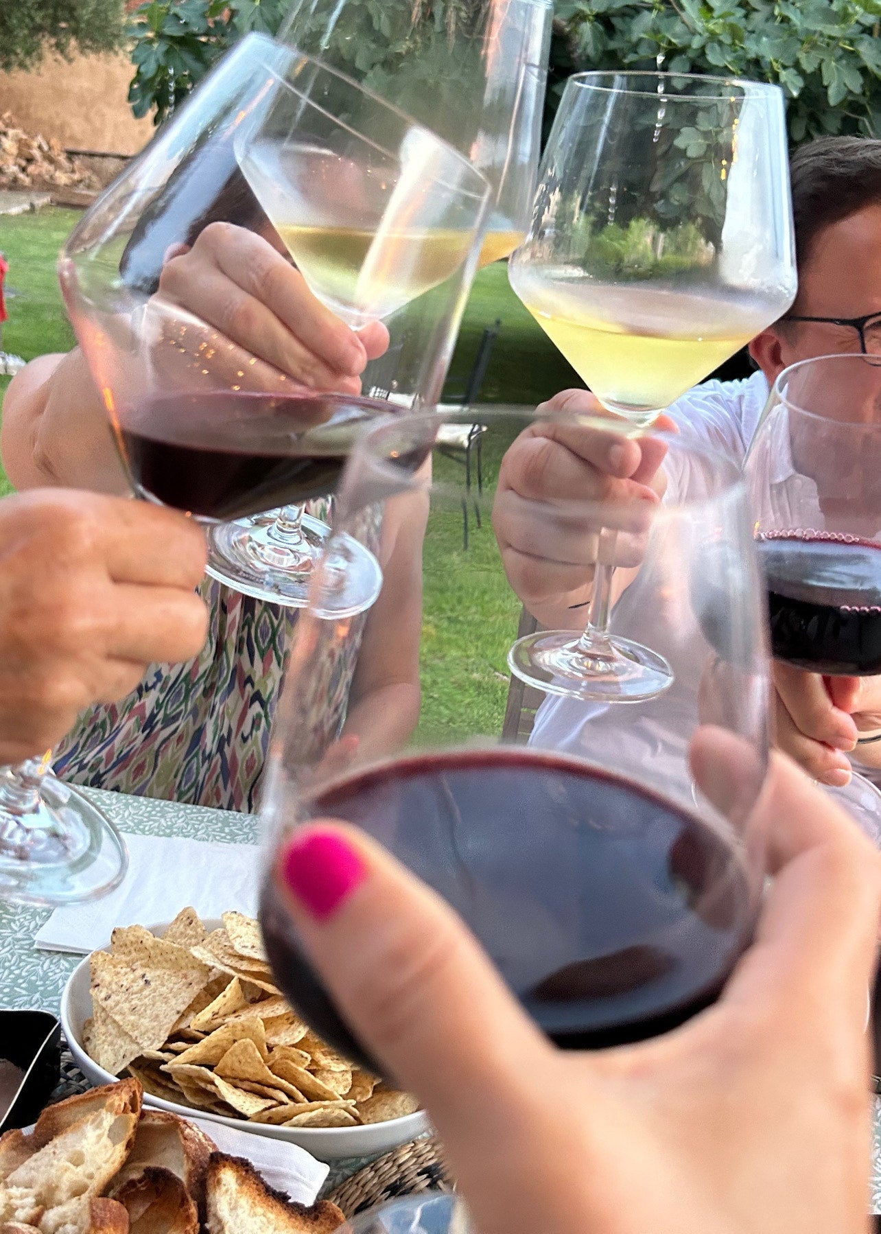 People enjoying a meal outdoors with wine glasses and snacks.