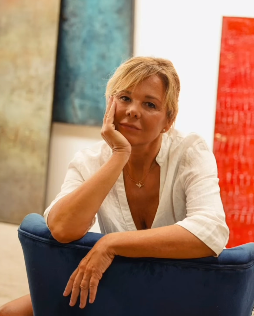 Woman sitting on a blue chair with abstract art in the background