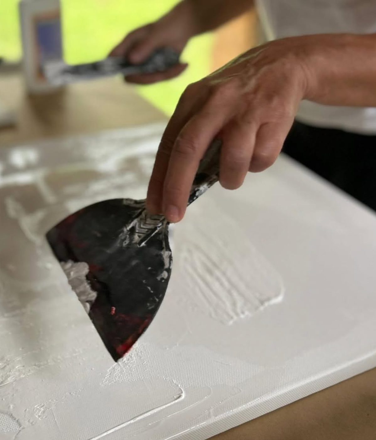 Person applying a black material to a white surface with a tool.