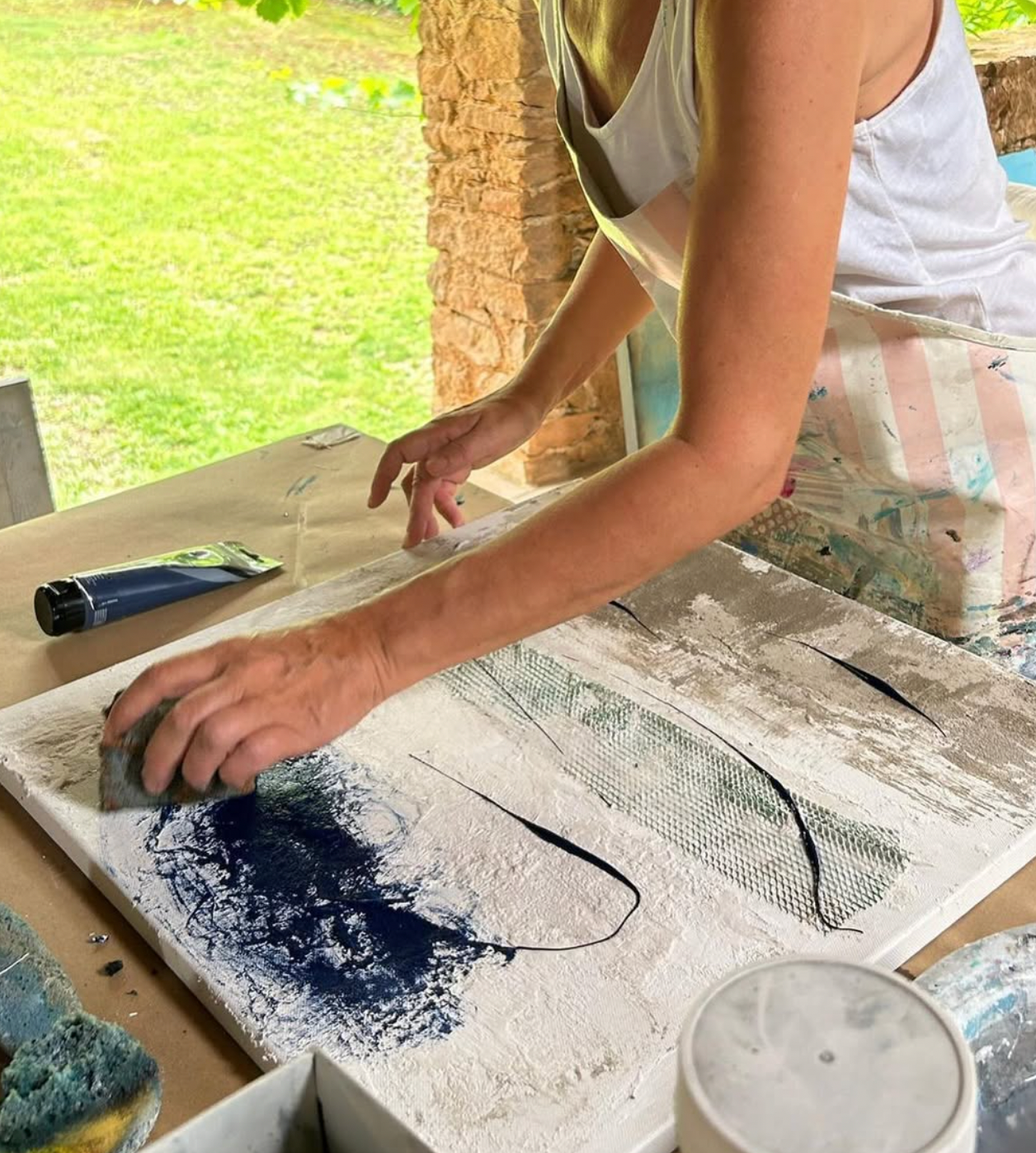 Person working on a craft project with materials on a table outdoors