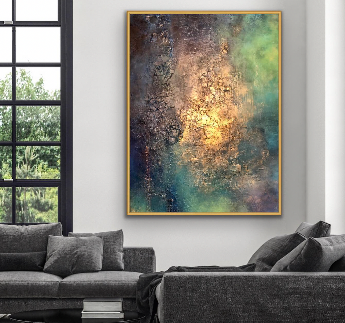 Abstract painting on a wall above a gray sofa in a room with large windows.
