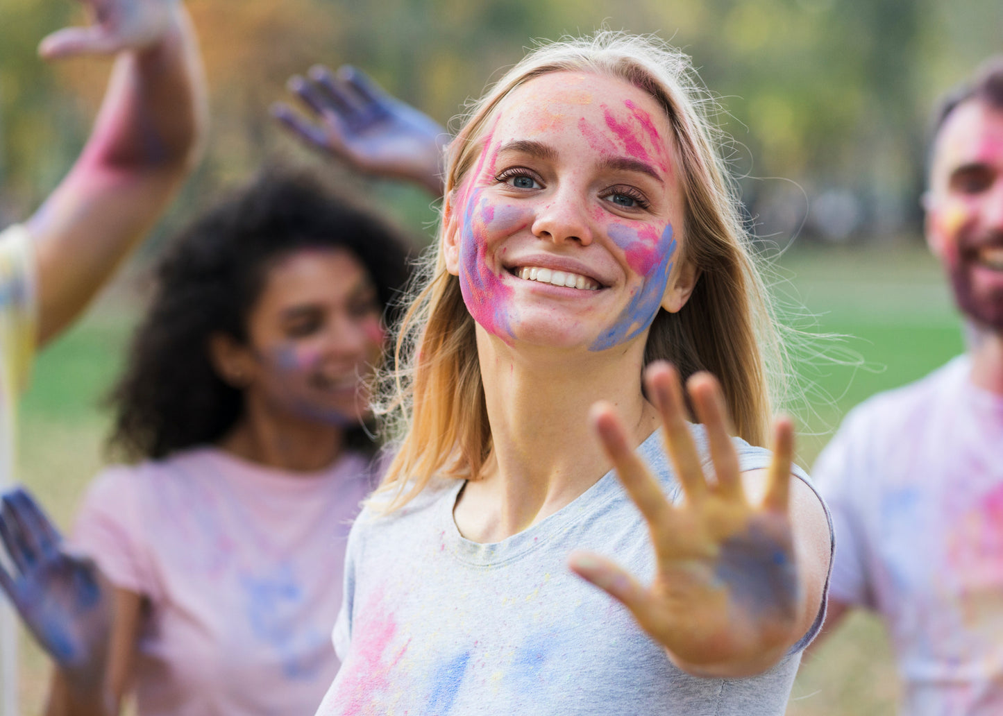 Woman with colorful face and hands in a park with friends