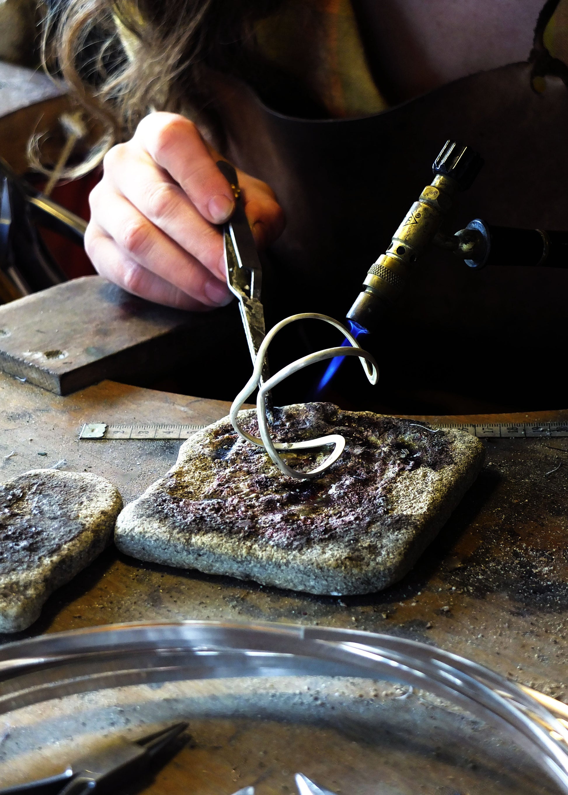 Person working with metal on a stone surface in a workshop setting
