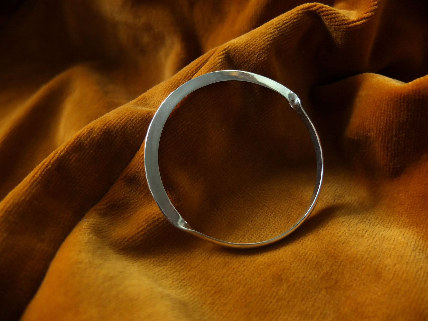 Silver ring on a textured brown fabric surface