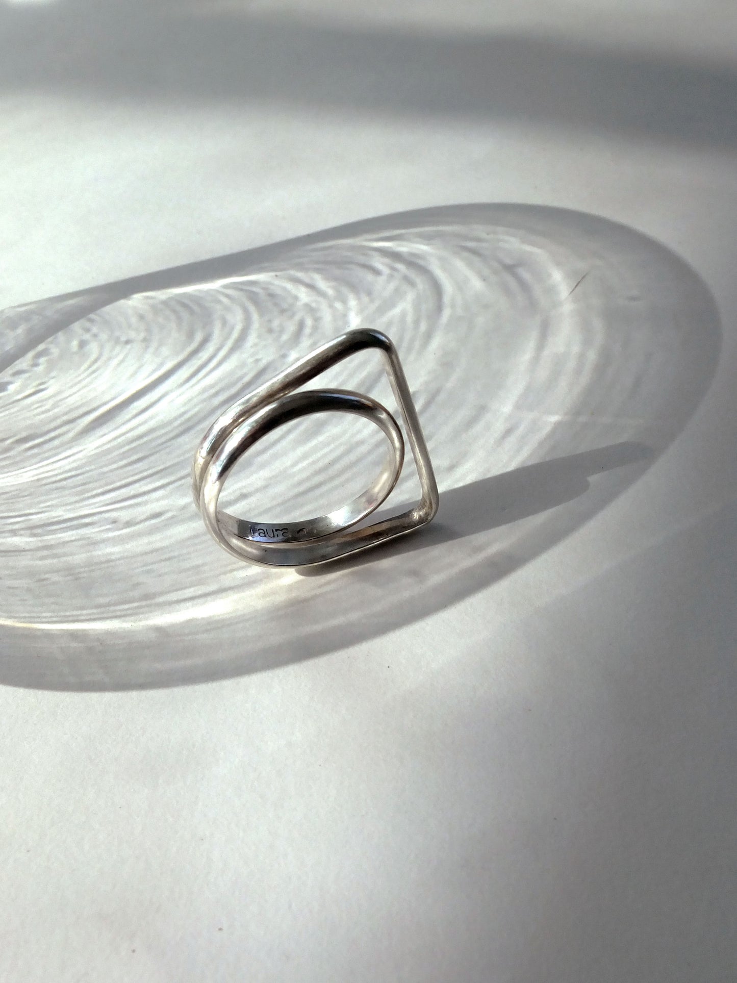 Silver ring with a geometric design on a light gray surface