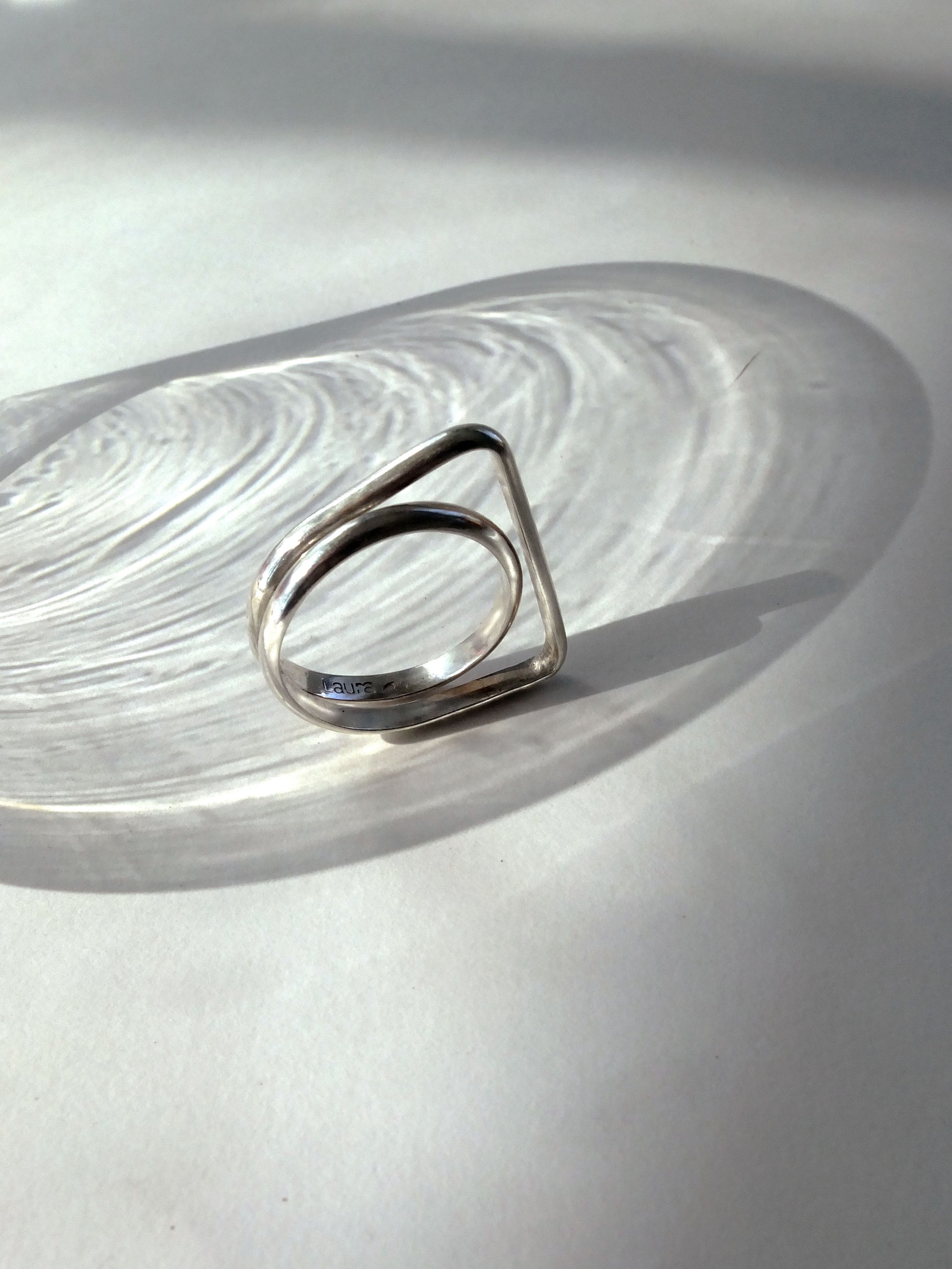 Silver ring with a geometric design on a light gray surface