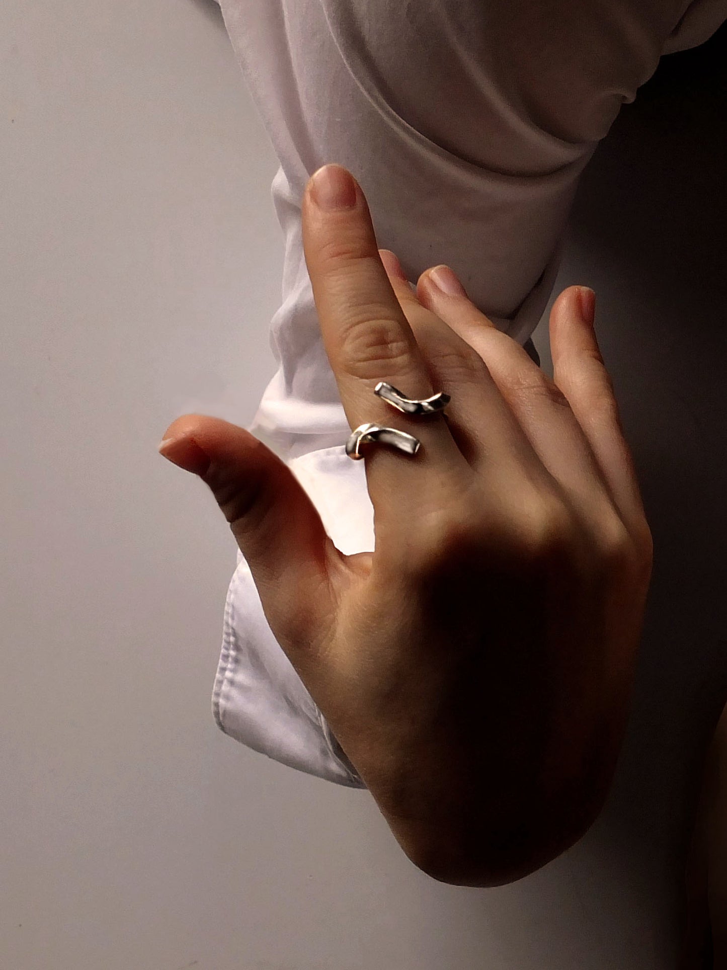 Hand wearing two rings on a plain background