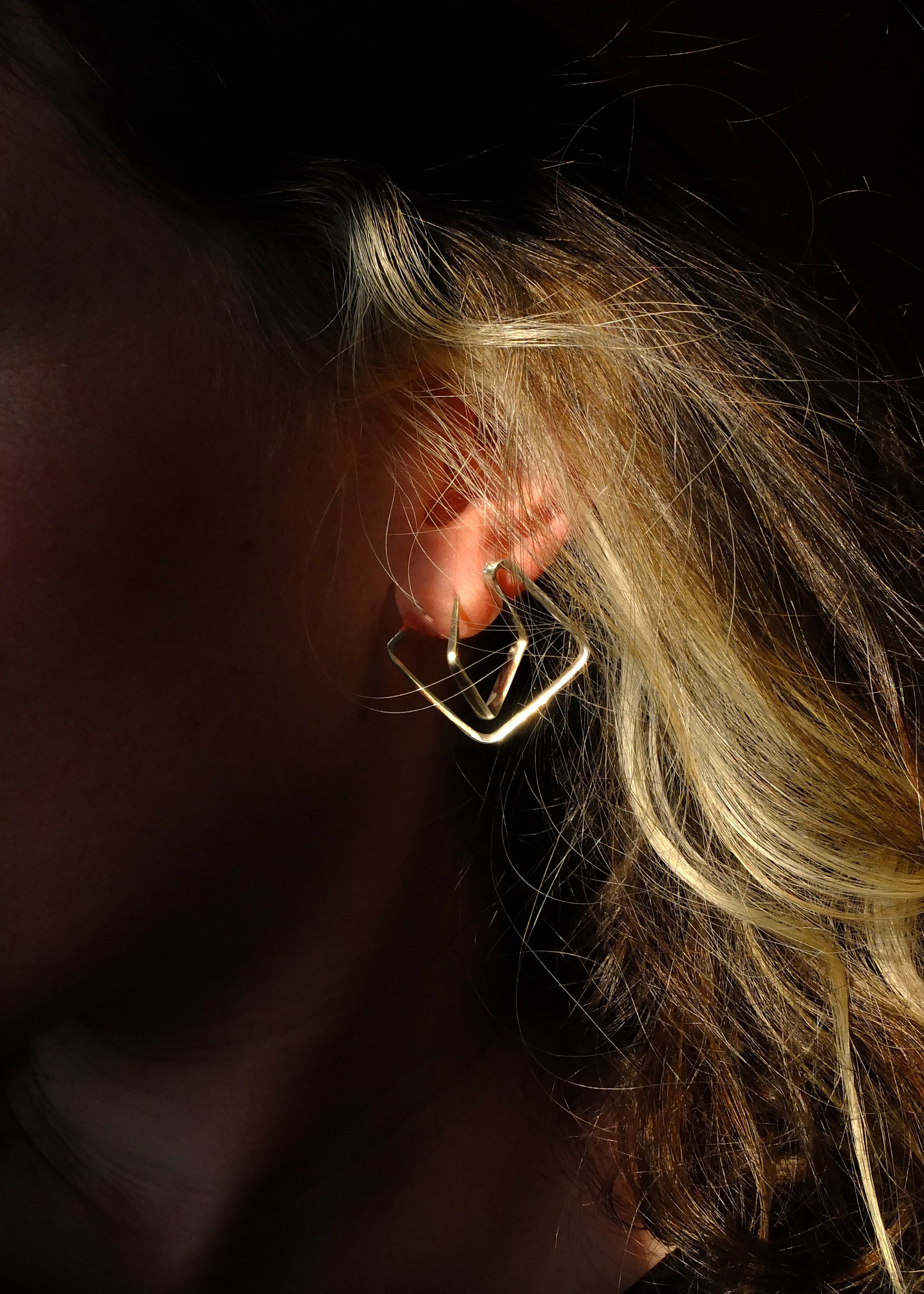 Close-up of an ear with a gold earring against a dark background