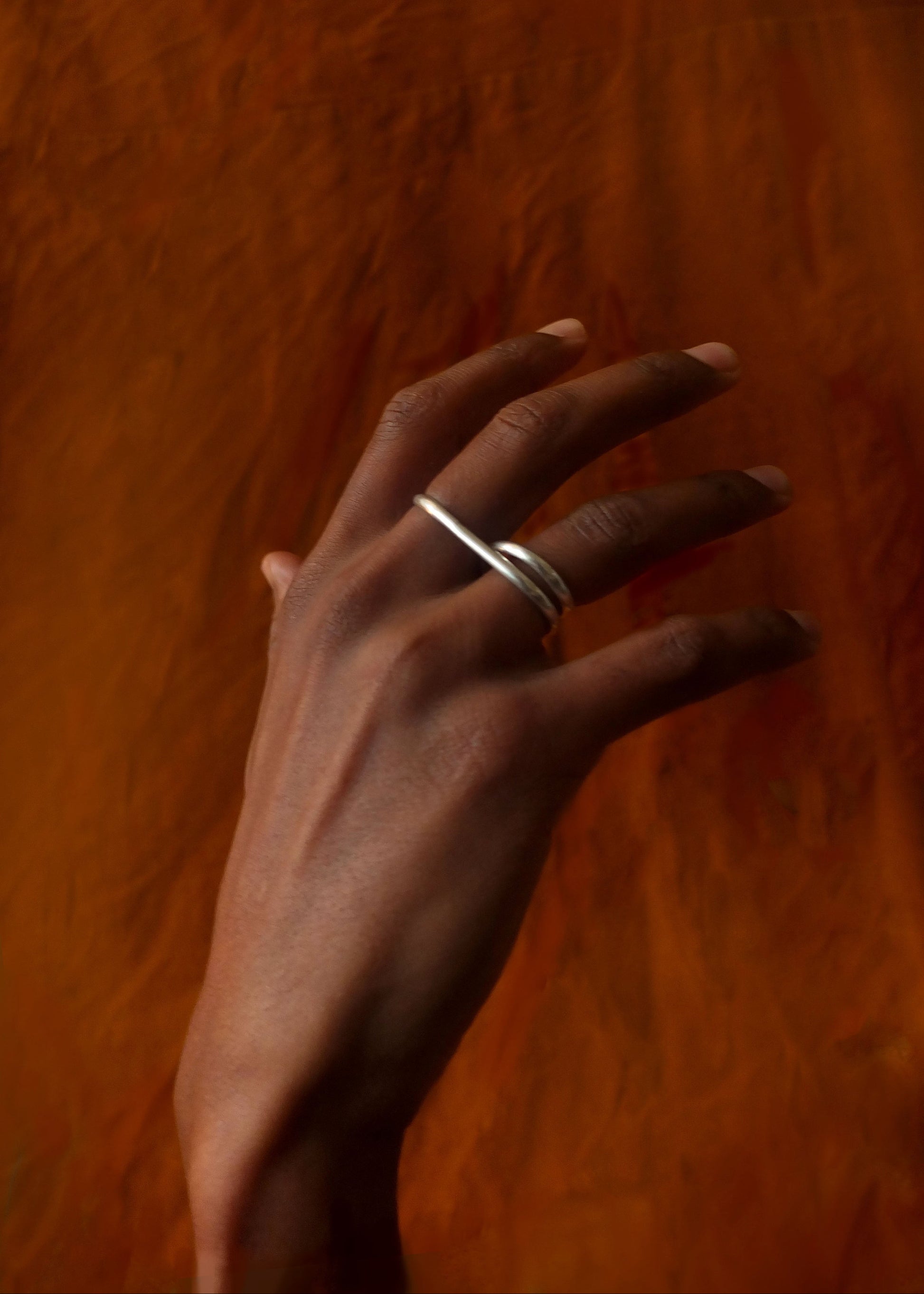 Hand wearing a silver ring on a wooden background