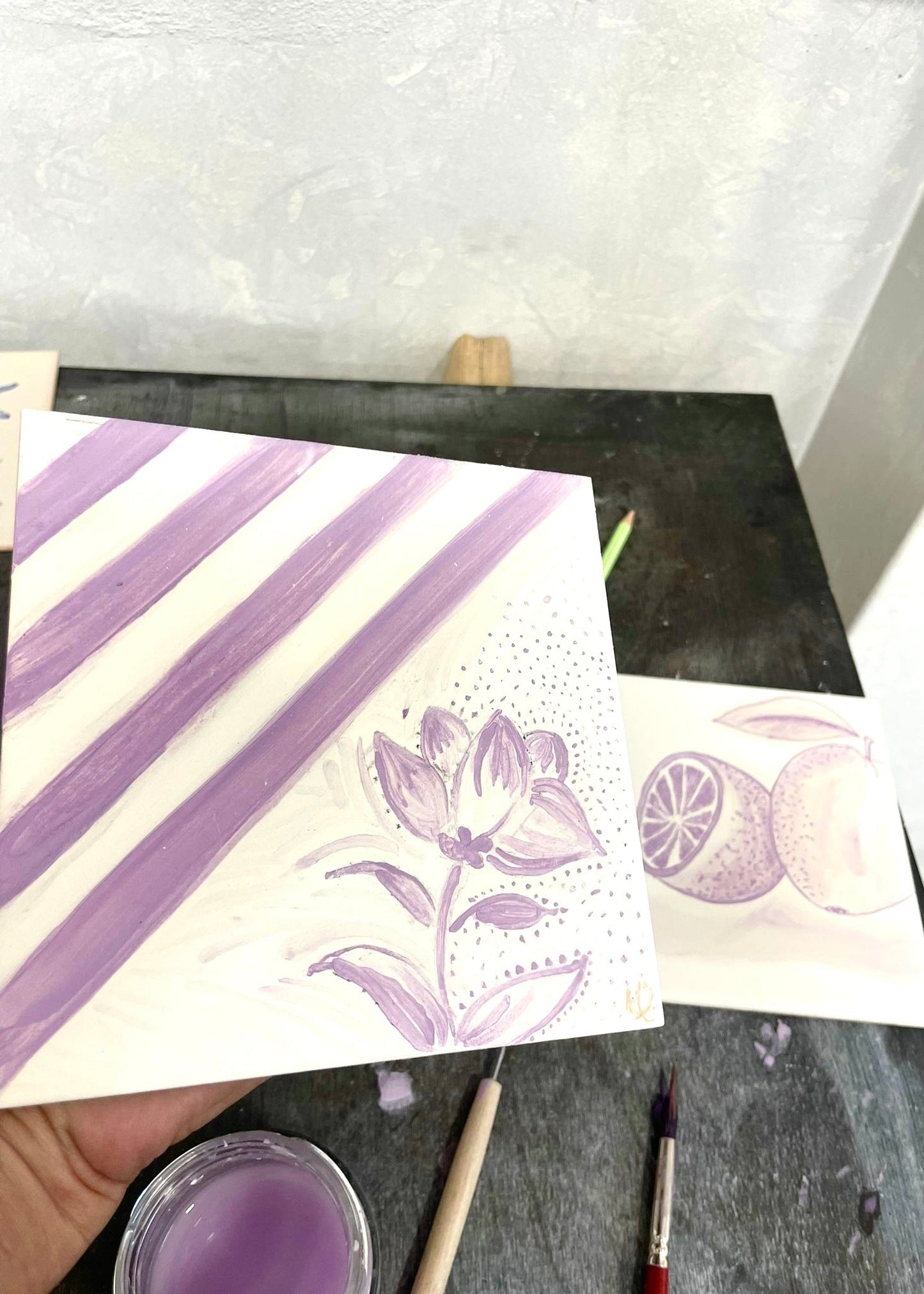 Card with purple floral design on a gray surface with paint supplies.