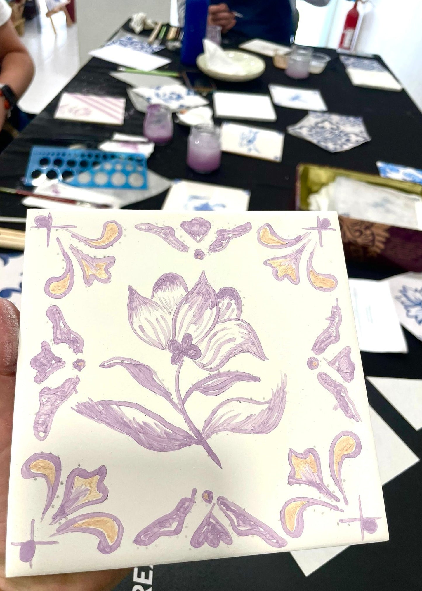 Card with floral design held by a hand, with a table in the background