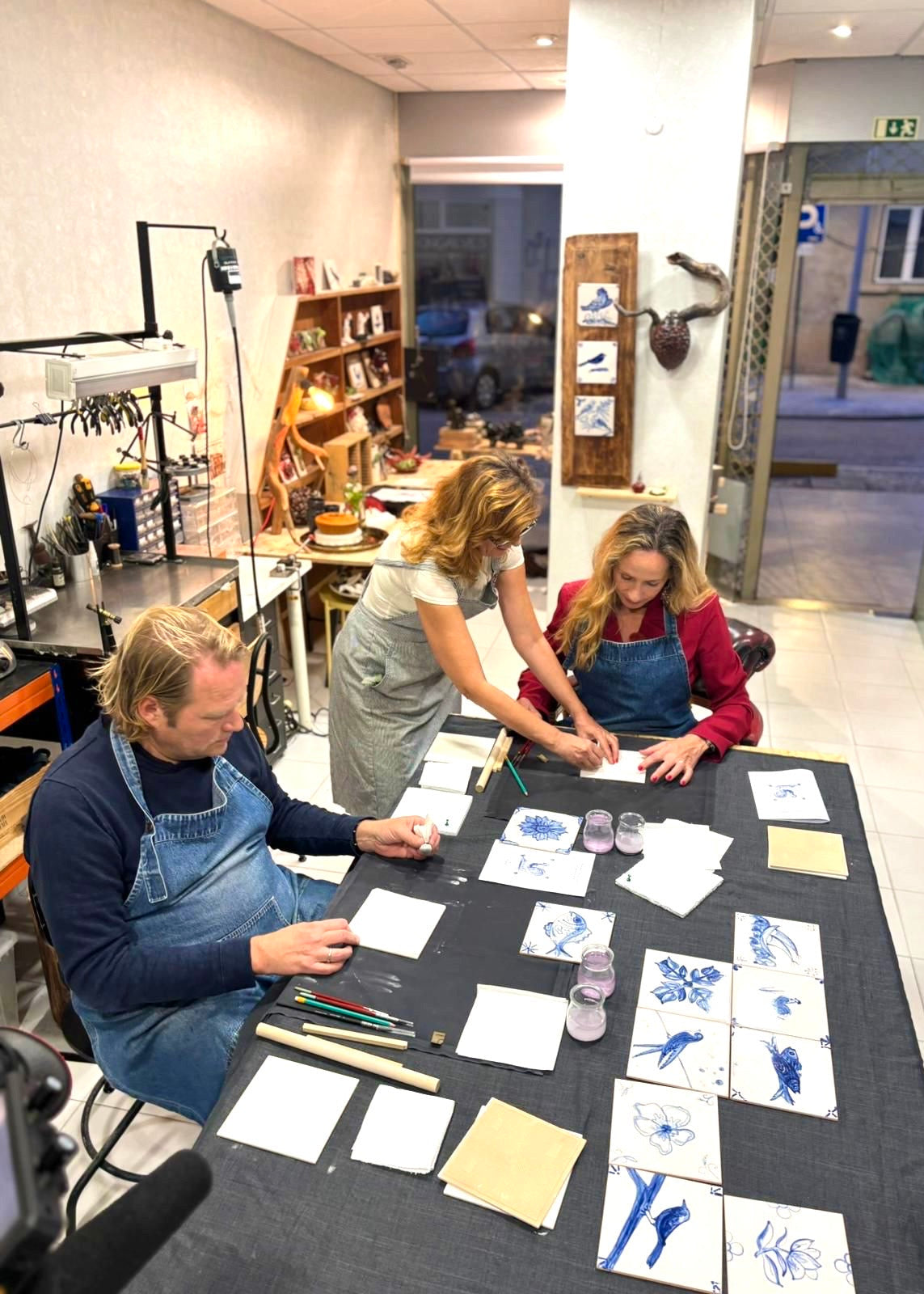 Two people working on art projects at a table with various materials and drawings.