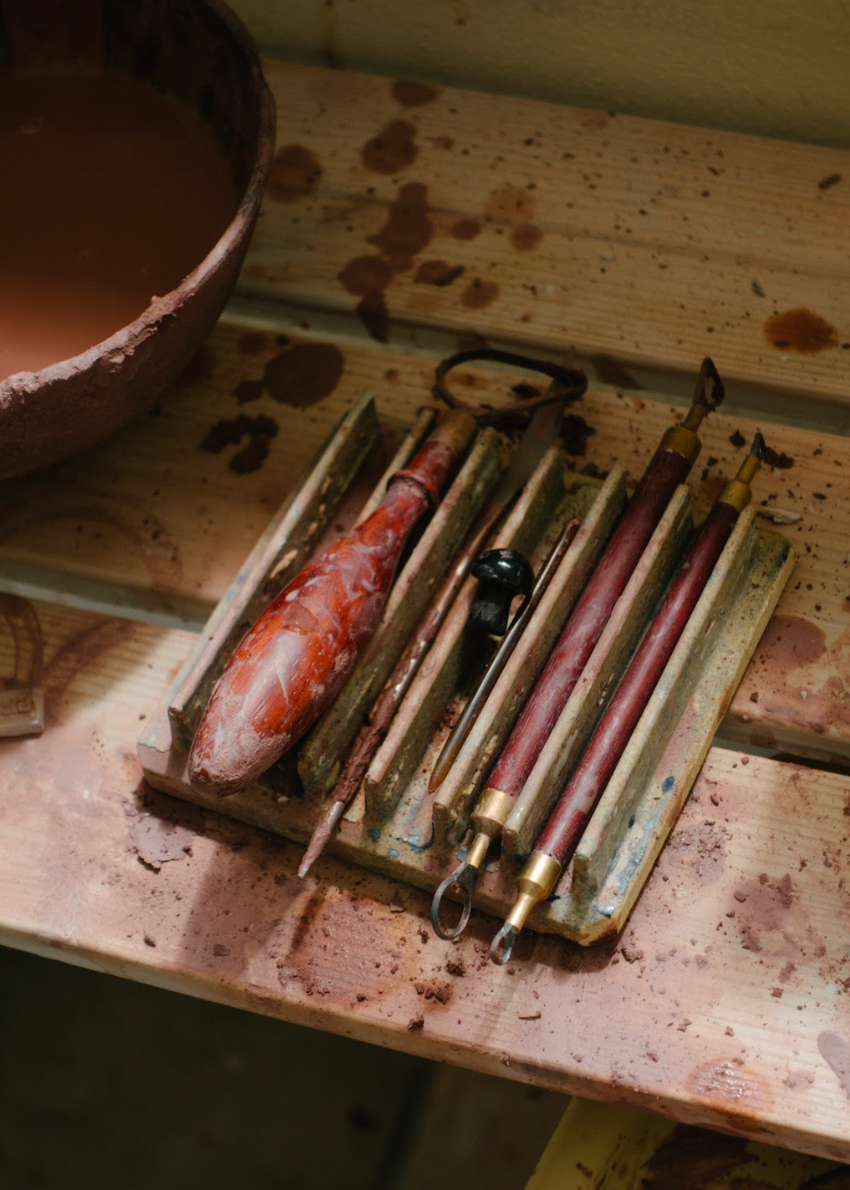 Set of tools on a worn wooden surface with a bowl in the background